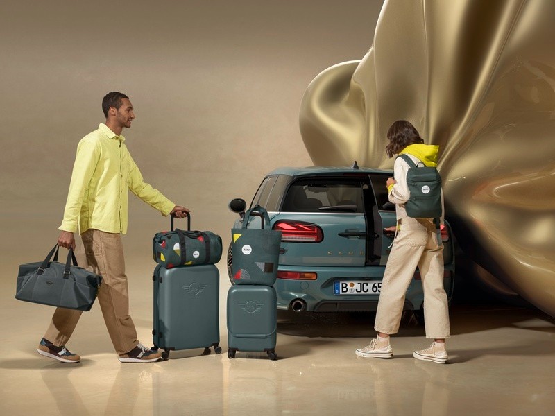 Homem e mulher com malas junto à traseira de um MINI.